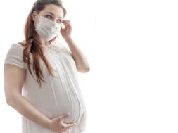 Young pregnant woman in protective medical mask copy space.