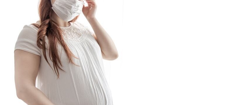 Young pregnant woman in protective medical mask copy space.