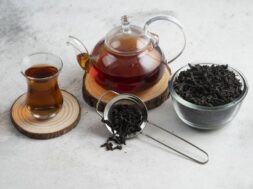A glass teapot with tea on a wooden board