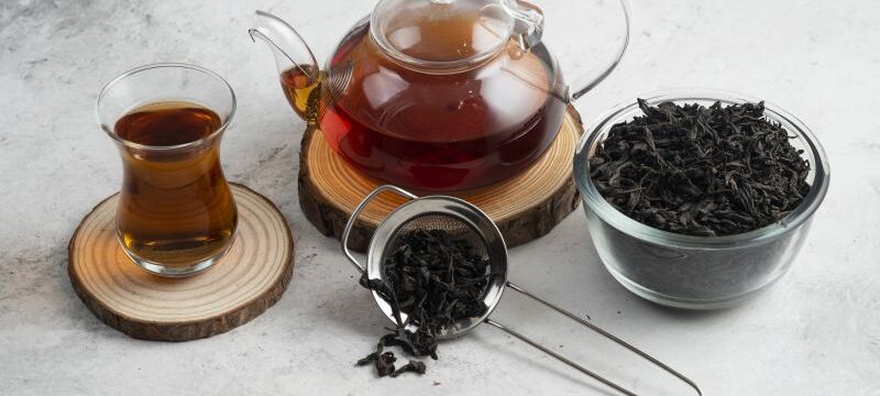 A glass teapot with tea on a wooden board
