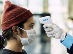 woman-medical-mask-getting-her-temperature-measured-by-electronic-thermometer
