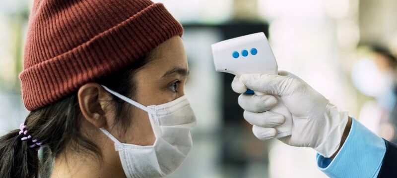 woman-medical-mask-getting-her-temperature-measured-by-electronic-thermometer