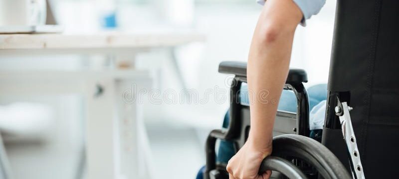 woman-wheelchair-next-to-office-desk-hand-close-up-unrecognizable-person-56793298