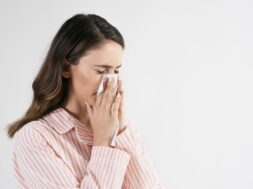 Young woman blowing her nose in studio shot