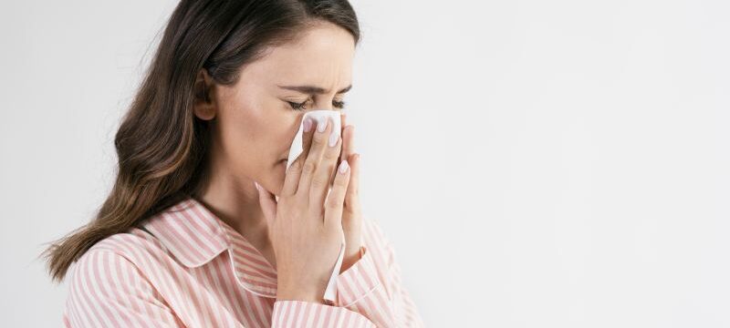 Young woman blowing her nose in studio shot