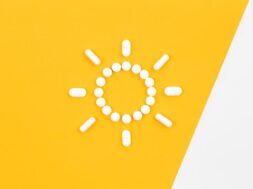 Pills in the shape of the sun, on a yellow background, flat lay.