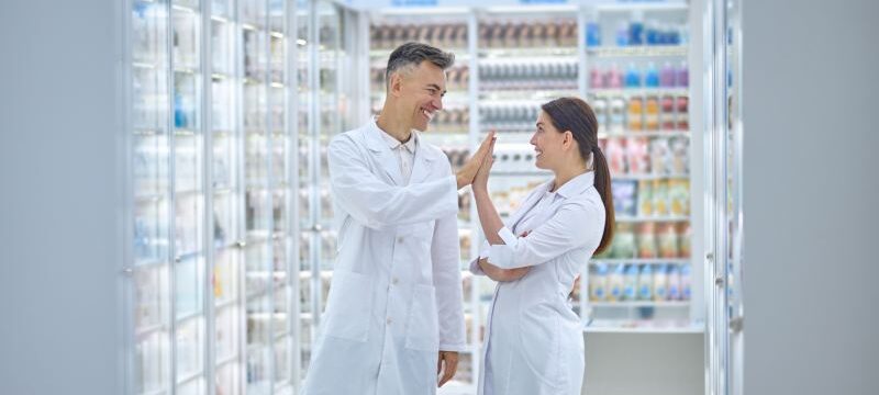 Two people in lab coats feeling good and smiling