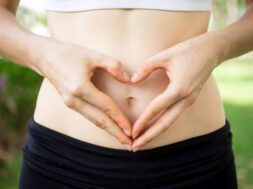 Close-up of female hands shaping heart on belly