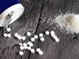 Sweetener tablet and sugar on wooden background, food