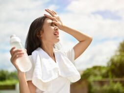 An exhausted Asian woman is fighting the heat wave while running in a park on a sunny day.
