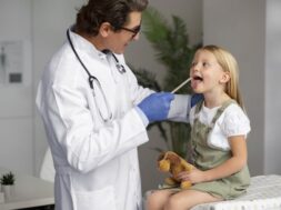 male-doctor-examining-little-girl-holding-teddy-bear-toy