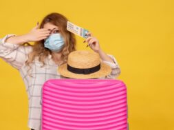 top-view-emotional-young-lady-wearing-mask-showing-ticket-standing-her-pink-bag