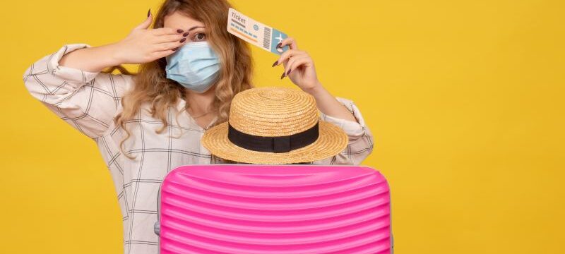 top-view-emotional-young-lady-wearing-mask-showing-ticket-standing-her-pink-bag