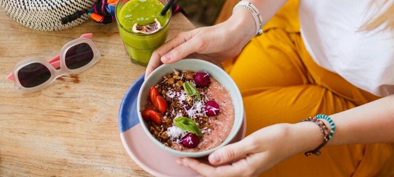 woman-holding-smoothie-superfoods-bowl-topped-with-chia-granola-avocado