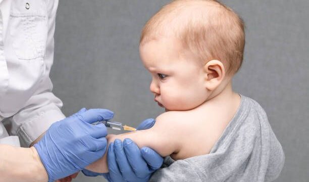 Portrait of baby girl receiving vaccination.