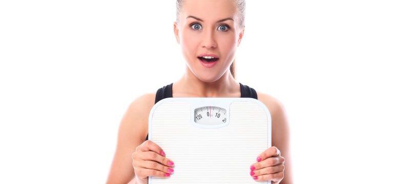 Beautiful fitness girl holding scales