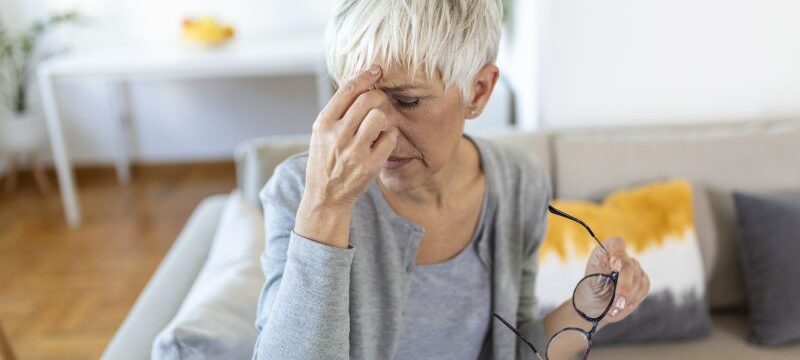 Senior woman in glasses rubs her eyes, suffering from tired eyes, ocular diseases concept