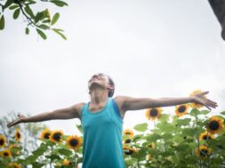 Beautiful woman with raising hands in a field of sunflowers in t