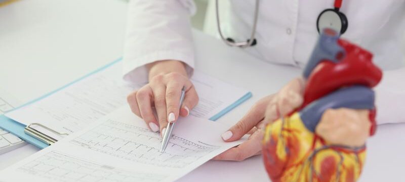 Cardiologist reads patient test results at table in hospital