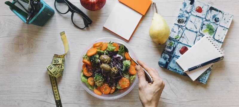 crop-hand-mixing-salad-office