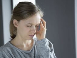 Sick woman at home massaging left temple with hand