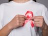 World Breast Cancer Day Concept. Health care woman wore white t-shirt with red ribbon for awareness. Symbolic bow color raising on people living with women’s breast tumor illness