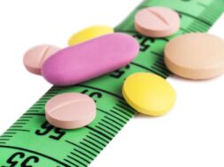 Closeup shot of the colourful drugs on the green tape measure on the white surface