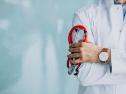 Young handsome physician in a medical robe with stethoscope