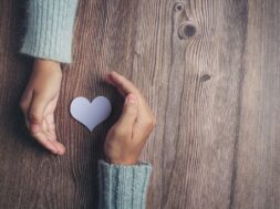 paper heart and couple’s hands on wooden table