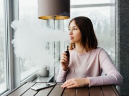 Modern girl smoking vape.Trendy new vaping device,smoke e-liquid