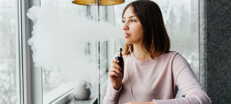 Modern girl smoking vape.Trendy new vaping device,smoke e-liquid