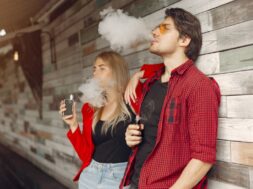 Stylish young couple with vape in a city