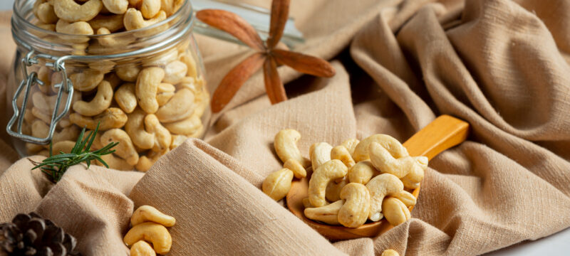 Raw cashews nuts in an open glass jar on marble background