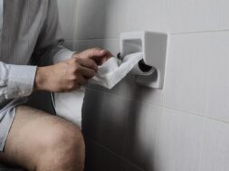 midsection-man-using-toiler-paper-while-sitting-bathroom-home_1048944-22839286