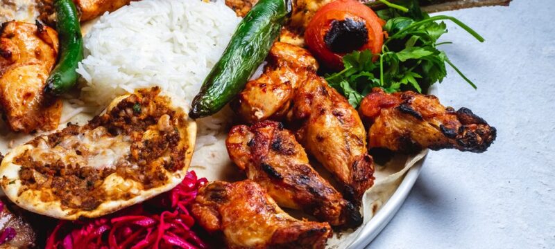 side-view-chicken-kebab-with-grilled-hot-green-pepper-tomato-pickled-cabbage-rice-pita_141793-4837