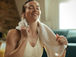 Sweaty athletic woman listening music over earphones at home.