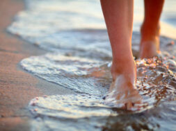 Female feet step on the sea wave. Summer vacations concept