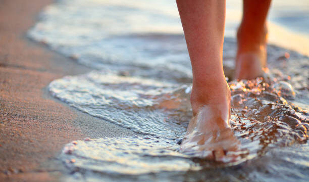 Female feet step on the sea wave. Summer vacations concept
