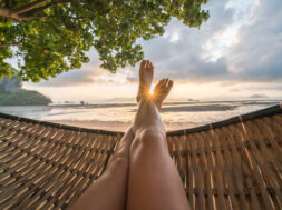 Female’s point of view from hammock on the beach at sunrise, barefoot.