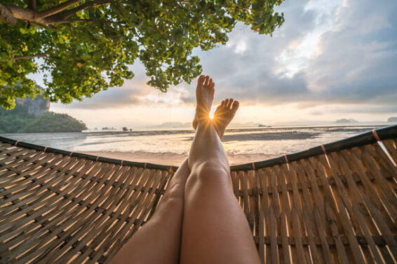 Female’s point of view from hammock on the beach at sunrise, barefoot.