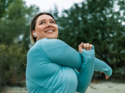 Young chubby woman stretching by the river