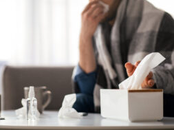Sick man sneezing nose, taking napkins, home interior
