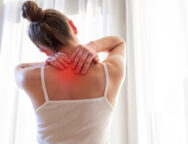 Young woman massaging her neck because of suffering from pain neck, stretching the muscles.