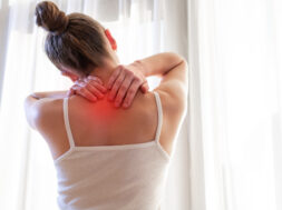 Young woman massaging her neck because of suffering from pain neck, stretching the muscles.