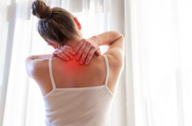 Young woman massaging her neck because of suffering from pain neck, stretching the muscles.