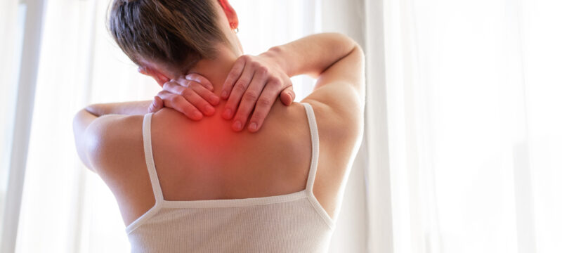 Young woman massaging her neck because of suffering from pain neck, stretching the muscles.